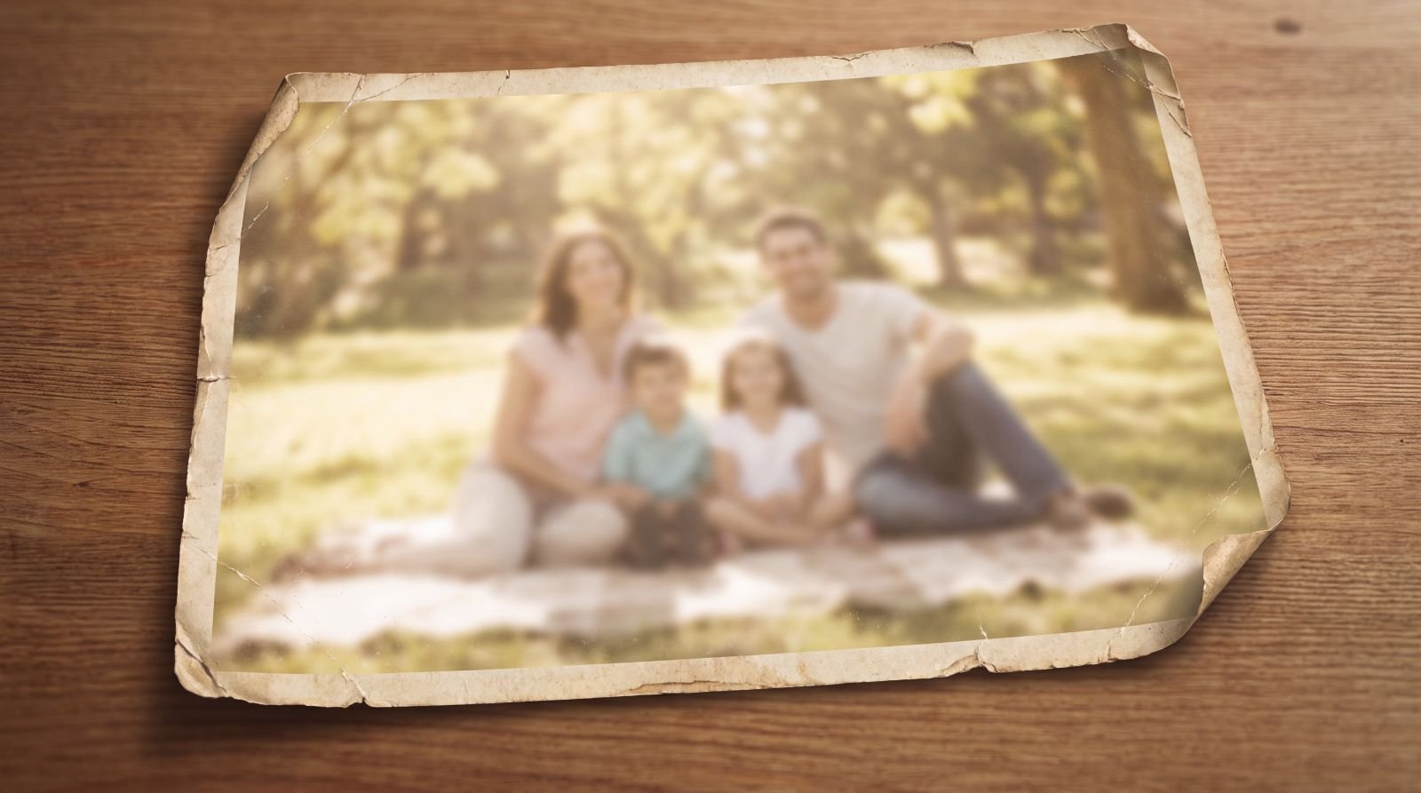 A faded, worn family photograph resting on a wooden table